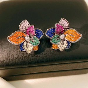 Macro shot of colorful zircon flower earrings on black leather textured jewelry box