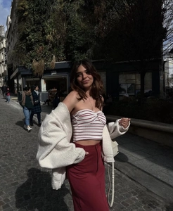 Street style view of a beige oversized coat with red striped tube top and midi skirt