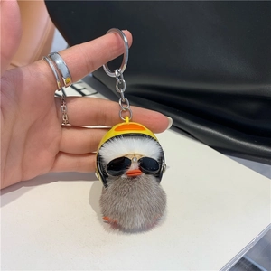 Close-up of a plush duck keychain with yellow helmet and glasses on black bag