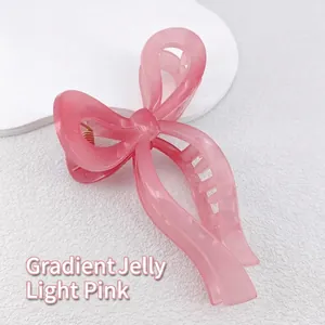 Detail of the translucent gradient pink bow hair claw clip on a white stone surface