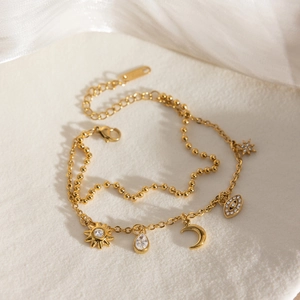 Détails d'un bracelet doré 18K avec breloques lune, étoile et incrustations de zircon