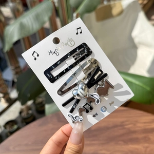 Close-up of a 5-piece music themed hair clip set featuring musical notes and piano patterns