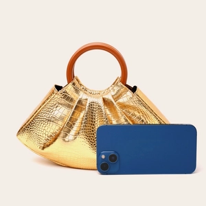 Golden crocodile pattern evening bag with vintage wooden handle next to a smartphone