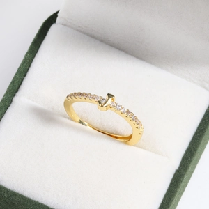 Detail of 18k gold plated letter ring with cubic zirconia in a green velvet jewelry box