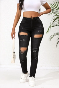 Détail du denim déchiré et des bords effilochés sur le jean slim noir à taille haute