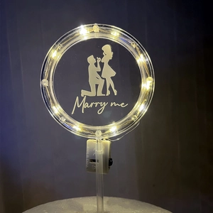 Close-up of a warm LED lighted acrylic round cake topper with Marry Me design