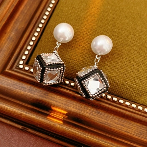 Detail view of pearl earrings with black cube pendant and sparkling cubic zirconia stones