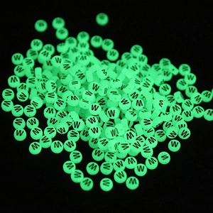 Macro shot of green luminous round beads with letter W for DIY jewelry making