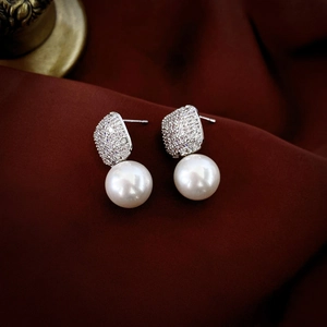Macro detail of luxury pearl earrings with sparkling cubic zirconia on silver studs