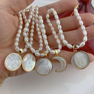 Handheld display of freshwater pearl necklace with mother of pearl Virgin Mary pendants