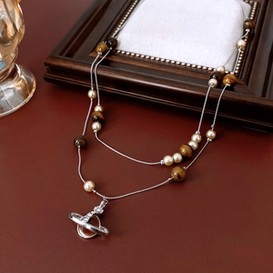 Detail of double-layer Saturn necklace with tiger eye stones and pearls on leather