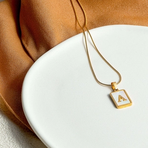 Gold stainless steel necklace with a square white shell pendant featuring a 3D letter A