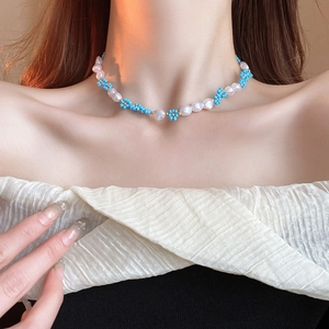 Floral bead choker necklace with blue flower accents and white pearls on woman's neck