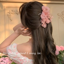 Detail of a large pink floral hair tie worn on a model's hair with a romantic vibe