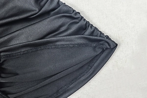 Close-up of black ruched fabric texture and professional stitching on the bodycon dress