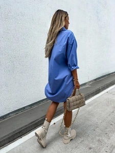 Street style view of a blue long-sleeved V-neck shirt dress paired with boots