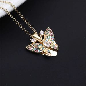 Macro detail of gold butterfly necklace with hollow wings and colorful crystal inlay