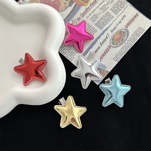 Y2K star-shaped hair clips in metallic colors on a decorative ceramic tray and newspaper