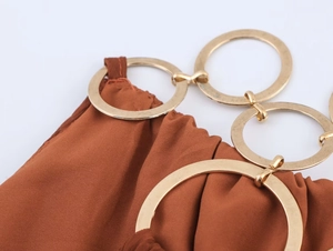 Detalle de la hebilla de metal dorado en la tela marrón del vestido tipo halter