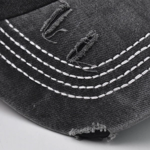 Macro detail of charcoal cotton cap brim with white stitching and vintage distressed effect