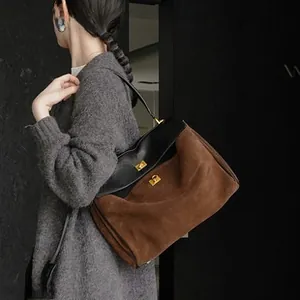 Detailed shot of leather tote bag featuring two-tone suede contrast and gold turn-lock closure