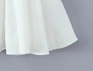 Detailaufnahme des weißen Chiffonstoffs und des zarten Saums des rückenfreien Kleids