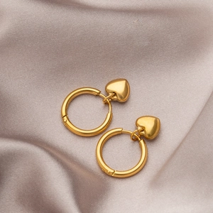 Minimalist gold heart hoop earrings on elegant champagne silk fabric background