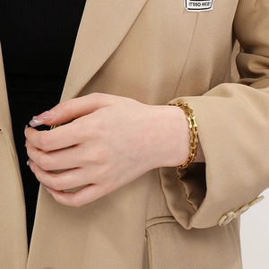 Close-up of gold titanium steel bone chain bracelet on model wrist with stylish suit