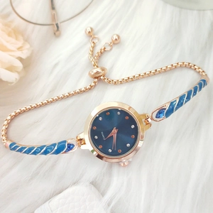 Detailed shot of a gold women's watch with blue enamel accents on a soft plush background