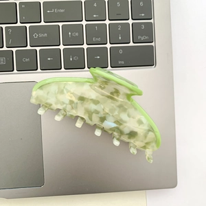 Detail of light green marble acetate hair claw clip on a laptop keyboard surface