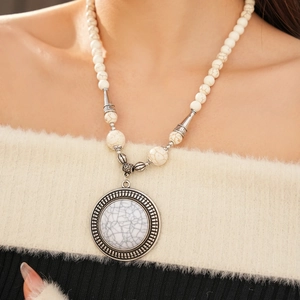 Close-up of bohemian beaded necklace featuring a carved silver round stone pendant