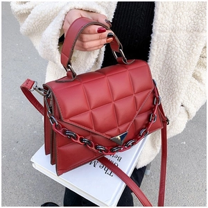 Detail of red quilted PU leather handbag with dual-tone plastic chain and metal clasp