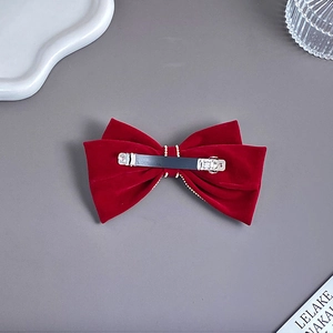 Detail of red velvet bow hair clip showing secure metal spring fastener and velvet texture