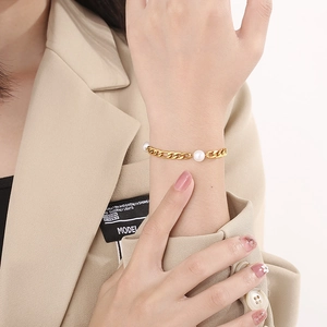 Detail of elegant gold chain bracelet with white pearls on a female model wrist