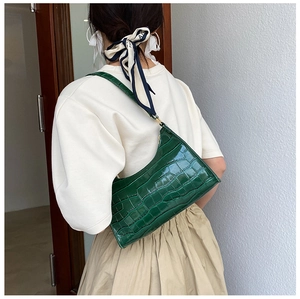 Rear view of model wearing a green crocodile embossed baguette bag with sleek half-moon shape