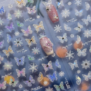 Macro shot of iridescent butterfly and snowflake nail stickers with crystal accents