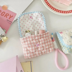 Close-up of pink quilted mini storage bag with heart stitching and cute wave ball trim