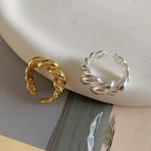 Close-up of gold and silver S925 sterling silver rope twist open rings on white ceramic