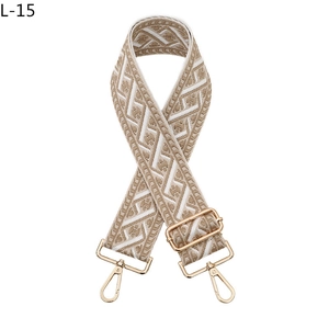 Close-up of geometric woven strap with Greek fret pattern and gold metal buckles