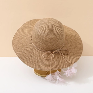 Detail of straw sun hat with ribbon bow and pink mesh flower tassels with pearls