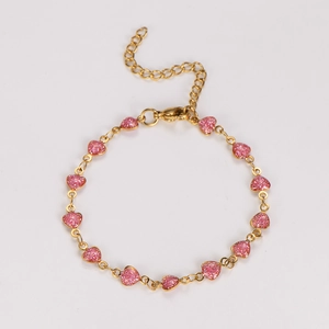 Detail of gold chain bracelet featuring a pink glitter heart pendant and lobster clasp