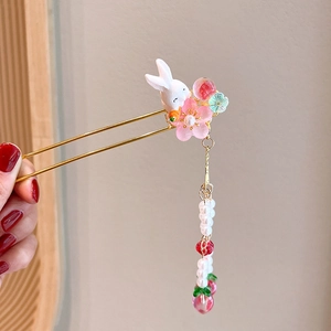 Detailed shot of golden hair pin featuring a white rabbit with pink floral tassel