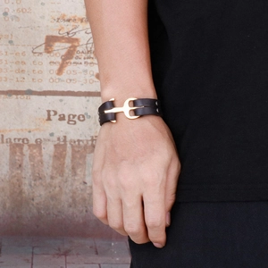Close-up of leather woven bracelet with golden anchor buckle and metal rivets