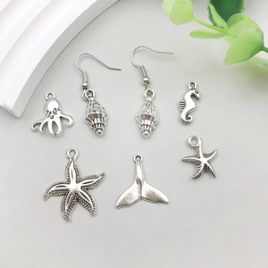 Flat lay of silver ocean charms featuring starfish, seahorse and whale tail pendants