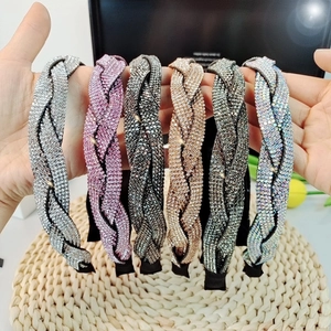 Close-up of six braided rhinestone headbands in various colors held by hands