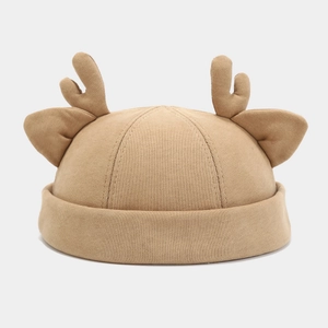 Detail of beige knit docker hat with decorative 3D antlers and ears on white background