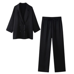 Detail eines schwarzen Doppelreiher-Blazers und Hose mit vertikaler Plissee-Struktur