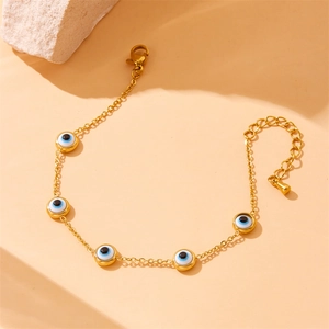 Gold stainless steel chain bracelet with five blue evil eye beads on stone pedestal