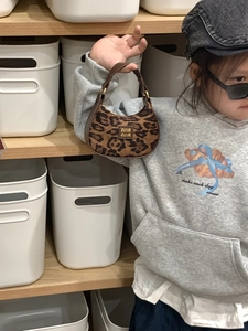 Détail d'un enfant portant un mini sac à main léopard avec poignée en cuir brun