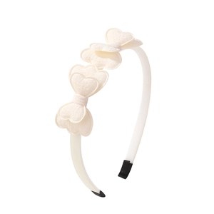 Detail of off-white fabric bow headband with heart-shaped layers and soft black end tips